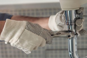 Handyman is repairing faucet of a sink at bathroom. Maintenance and household assistance concept